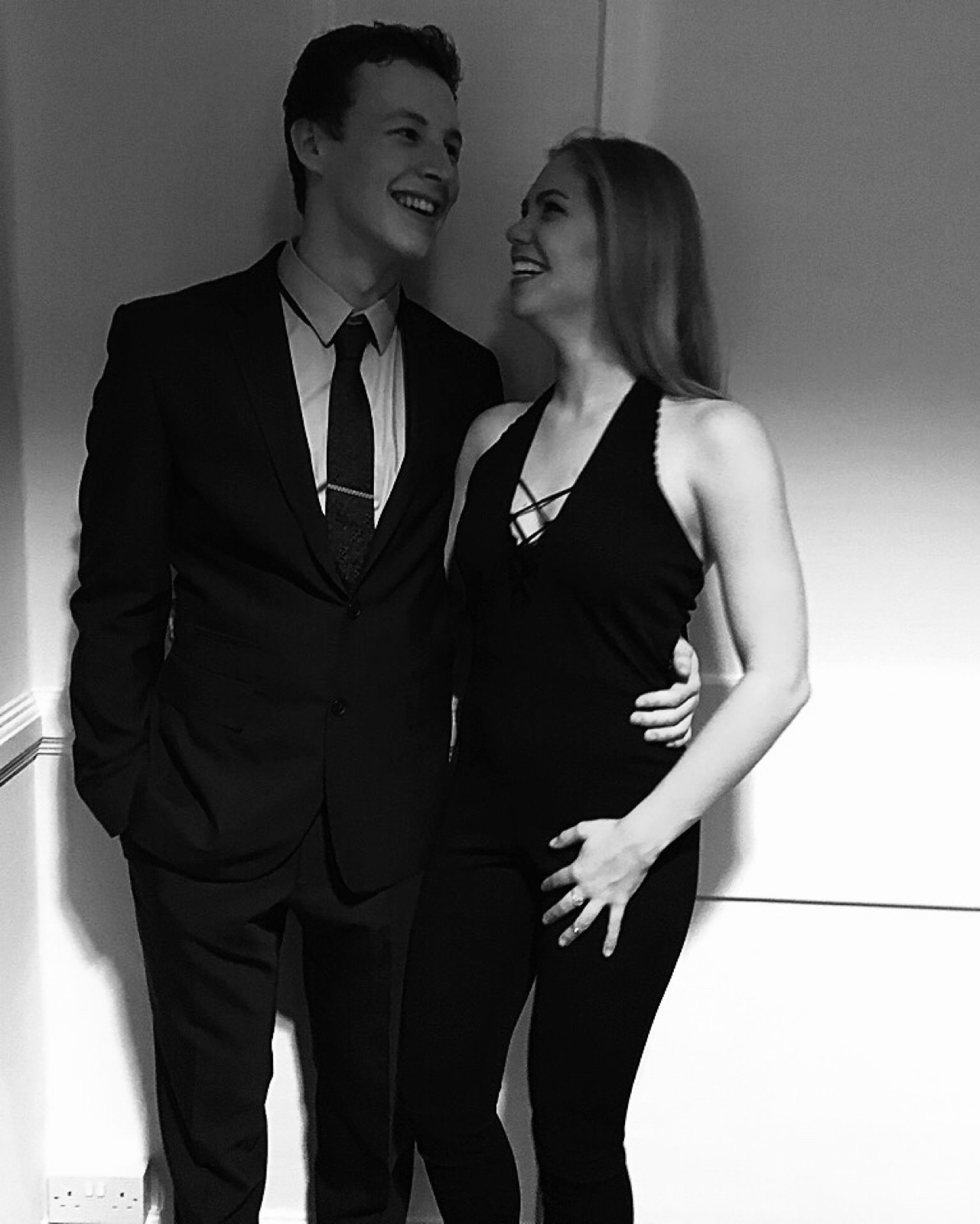 Chloe and Owain smiling at each other in black-and-white evening wear