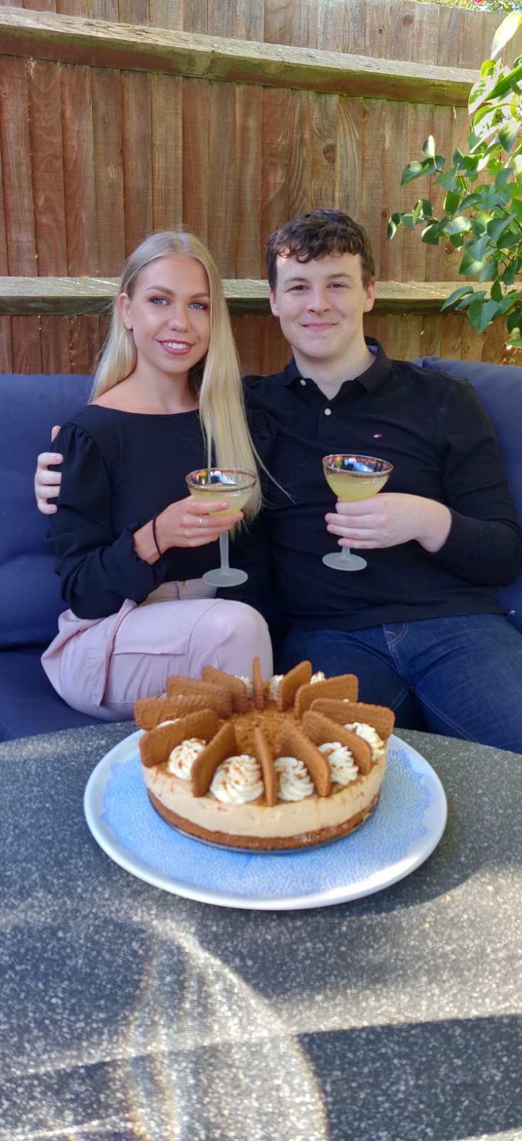 Chloe and Owain toasting cocktails beside a homemade cheesecake