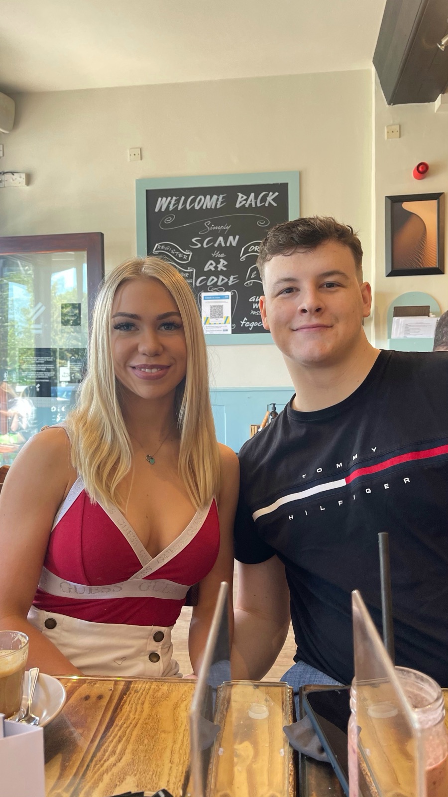 Chloe and Owain smiling together in a sunny cafe