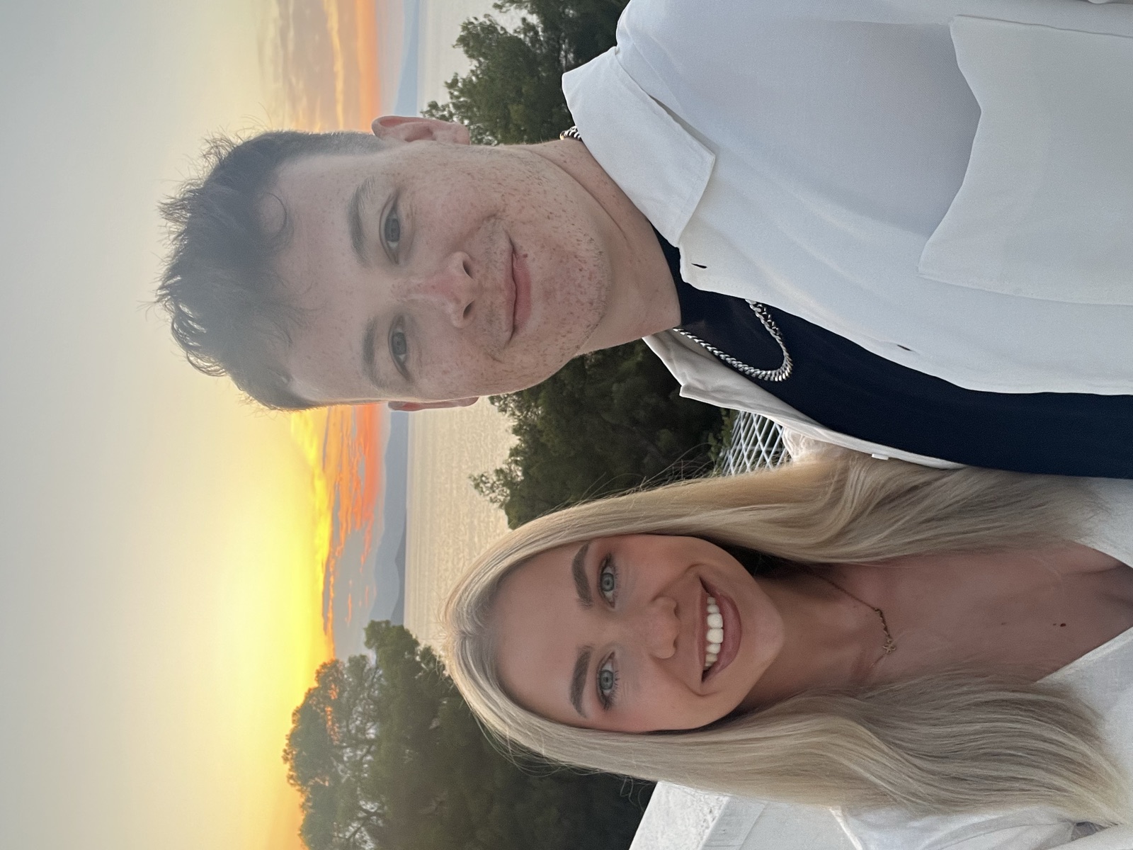 Chloe and Owain smiling together at a seaside sunset