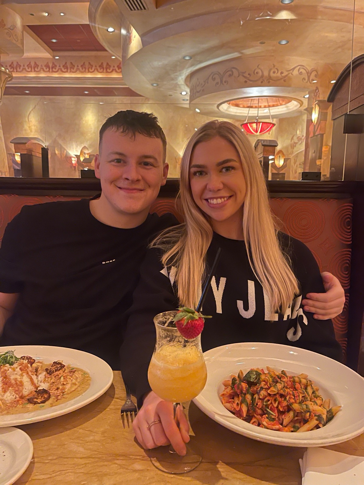Chloe and Owain smiling over dinner and a cocktail